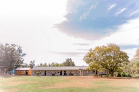 Hermitage House School is set against a backdrop of trees and green grass, creating a peaceful and picturesque environment.