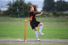 A boy wearing a brown and orange shirt prepares to throw a ball, showcasing focus and determination in his stance.